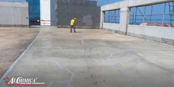 Concrete roof deck showing repaired cracks with a worker carrying out surface preparation.
